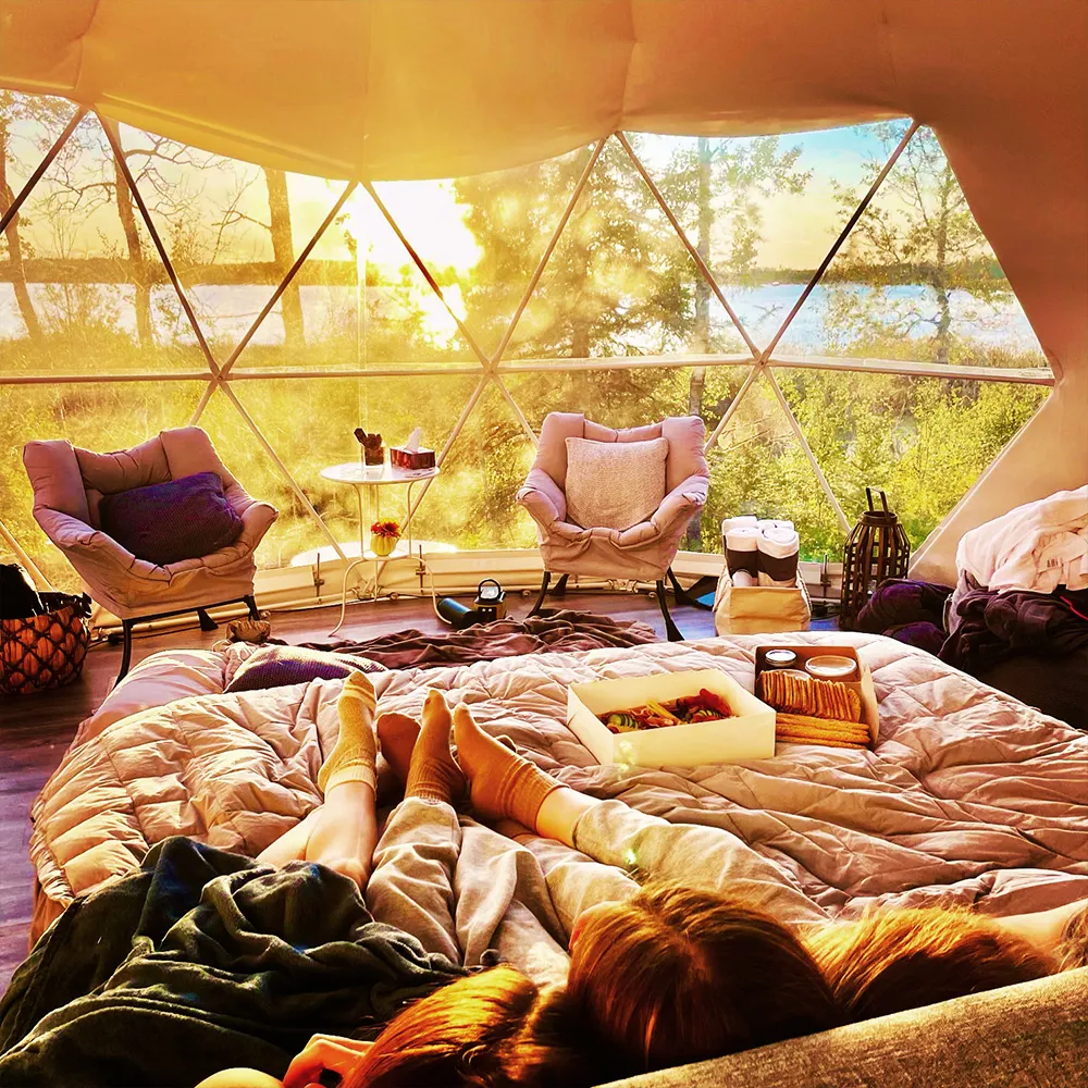 A couple snuggled up together on the bed of the ignis dome while watching the sunset and enjoying a charcuterie board