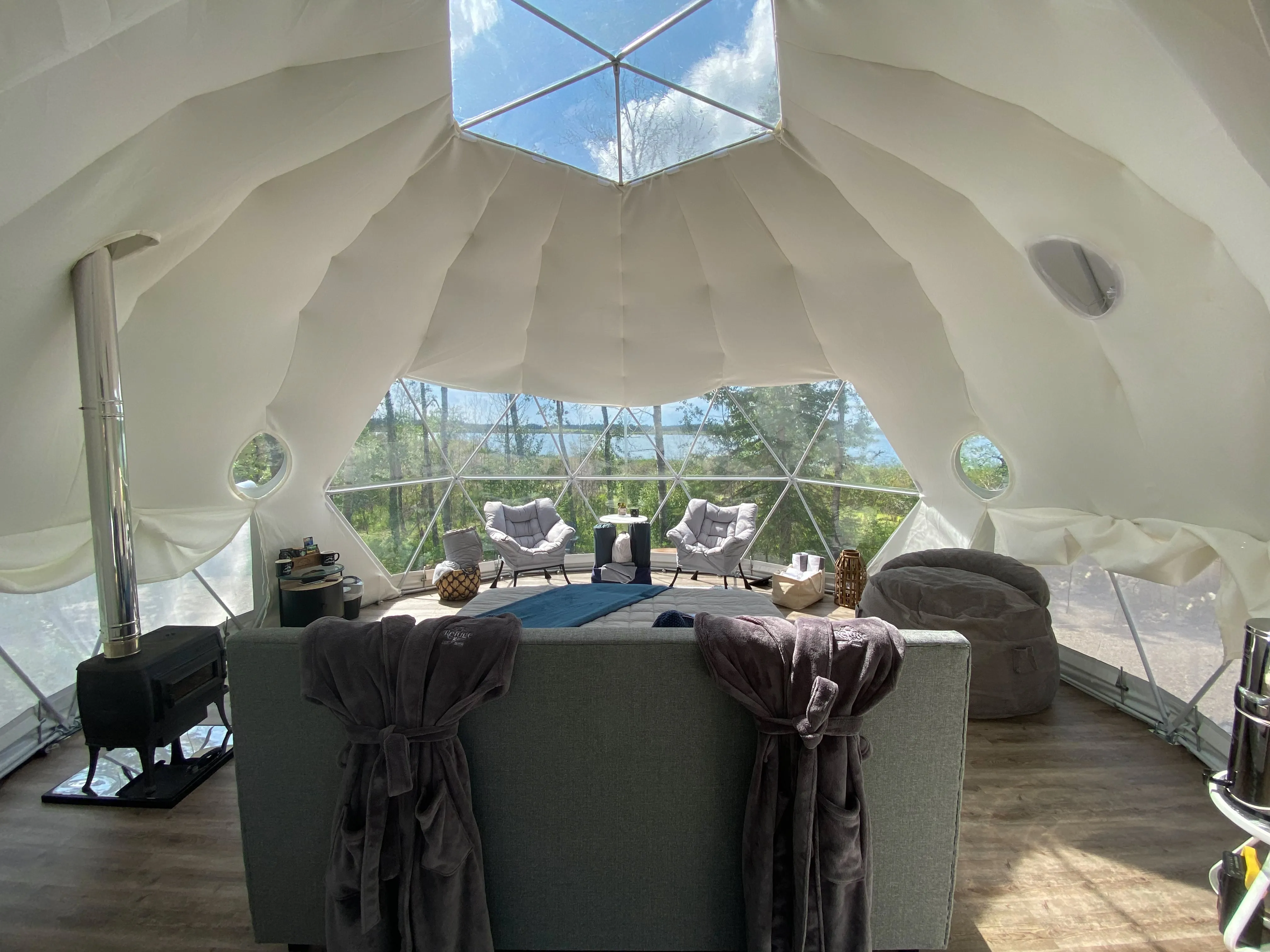 full interior shot of ignis dome. Featuring the bed, wood burning heater, large bean bag chair and two lounge chairs