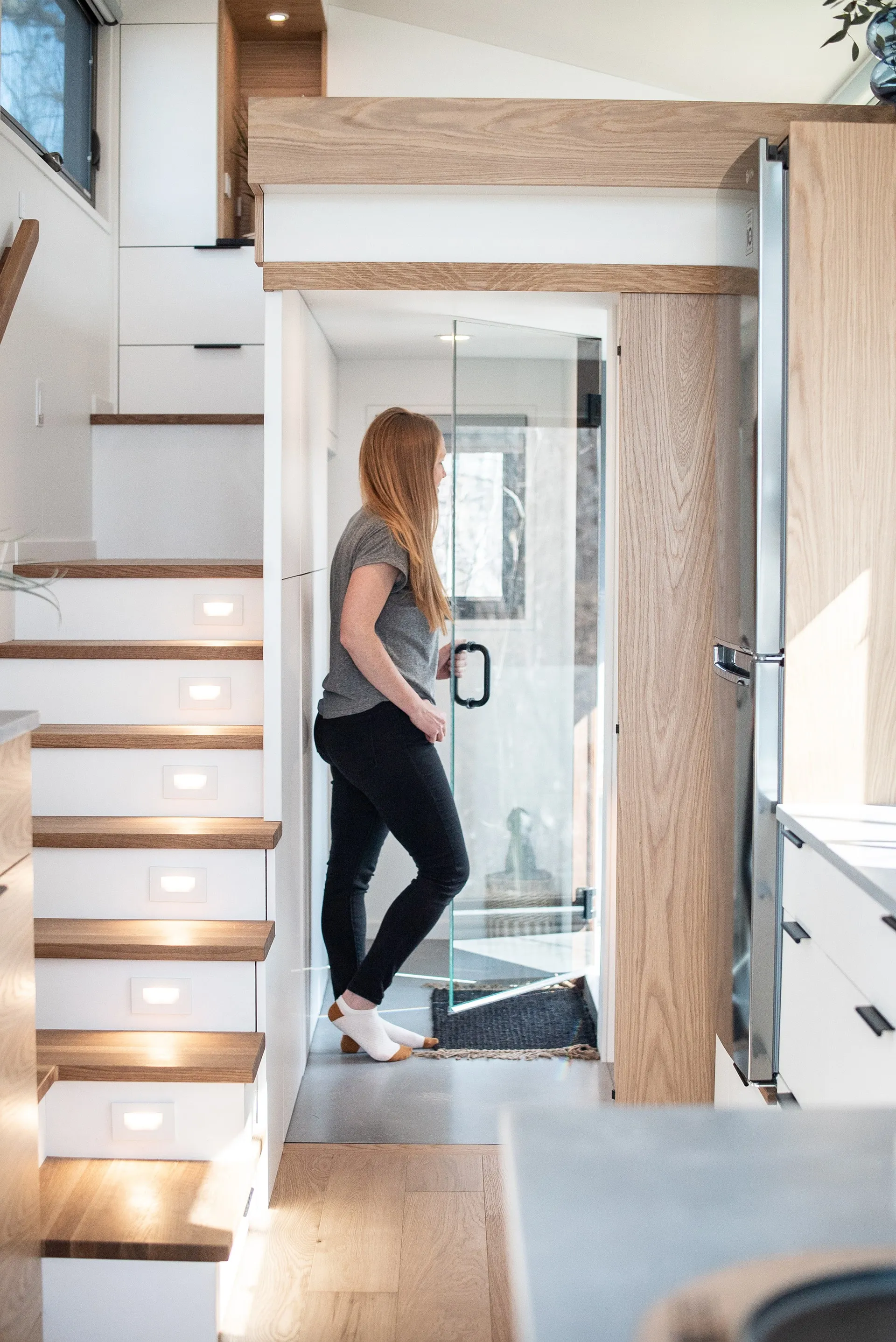 A woman opening the glass door entrance to the shower of the aqua tiny homes 