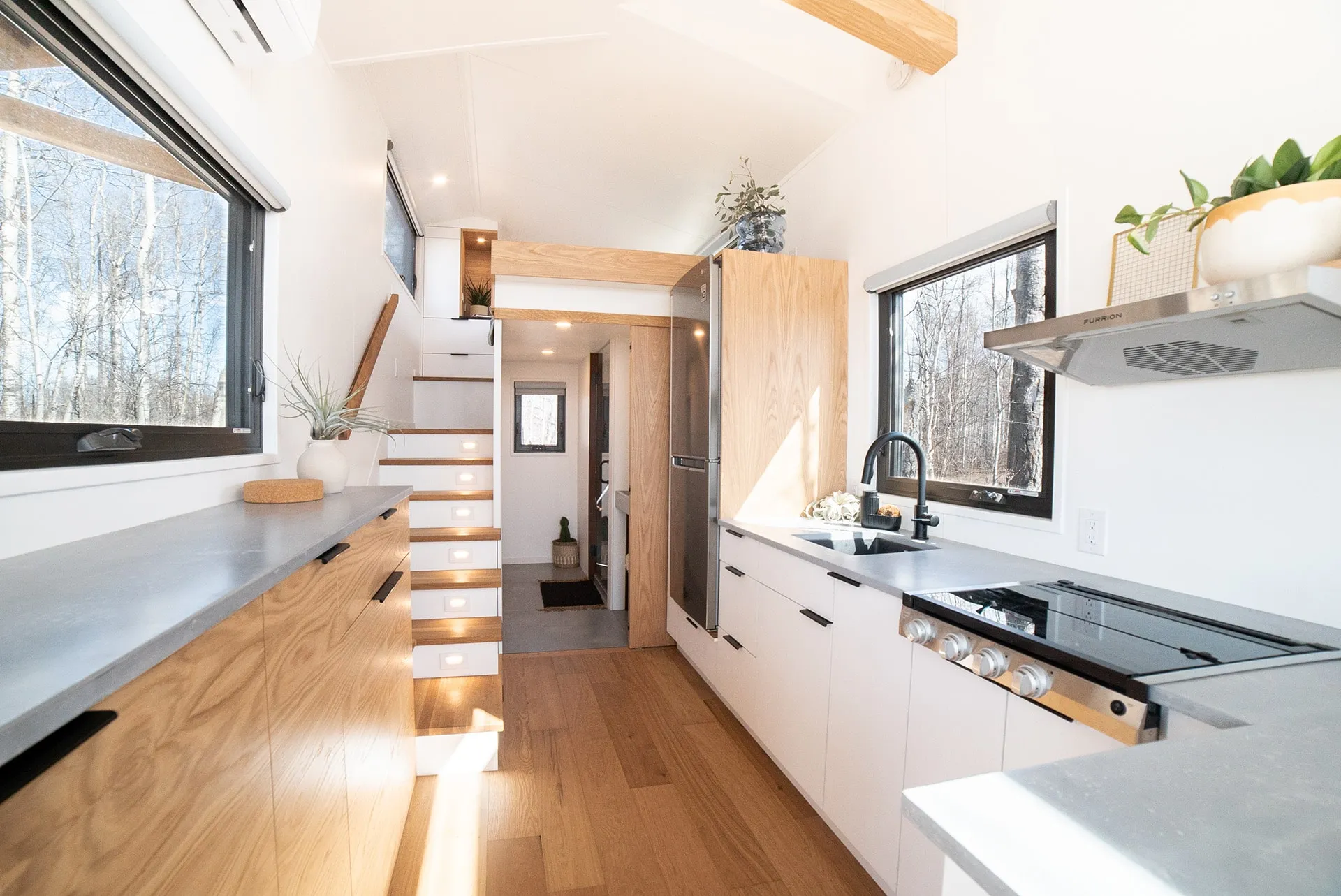 aqua tiny homes interior angled view of main floor with wider view of modern kitchen in a small space 